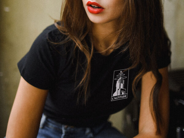 Black T-shirt with 'Altitude' logo on the chest, worn by a woman. Audiophile bar merchandise for music lovers, ideal for fans of vinyl mixes and high-quality sound experiences